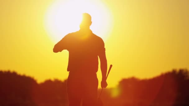 Golfista masculino jogando golfe ao pôr do sol — Vídeo de Stock