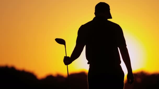 Golfista masculino jugando al golf al atardecer — Vídeos de Stock