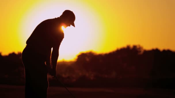 Golfista masculino jugando al golf al atardecer — Vídeos de Stock