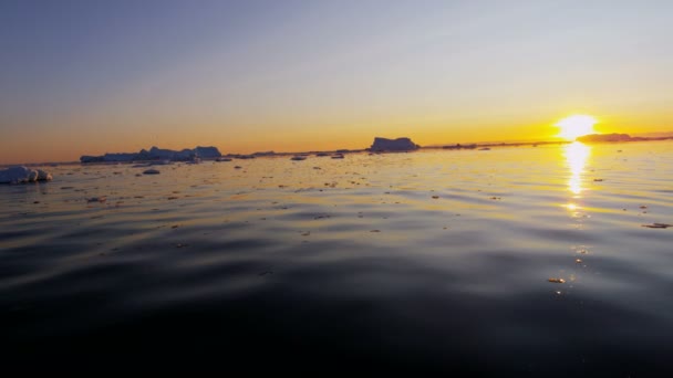 Témpanos glaciares flotando en el agua al atardecer — Vídeos de Stock