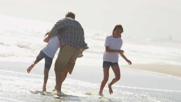 Padre con hijas jugando en la playa — Vídeo de stock