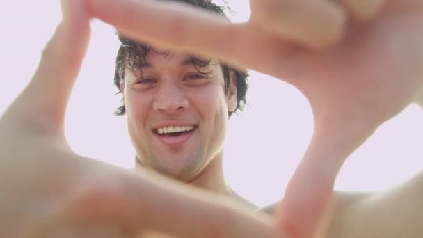 Man on beach making finger frame — Stock Video