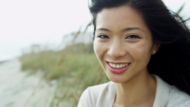 Азіатський жінка на пляжі, посміхаючись на камеру — стокове відео