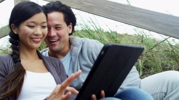 Пара на пляжі з бездротовим планшетом — стокове відео