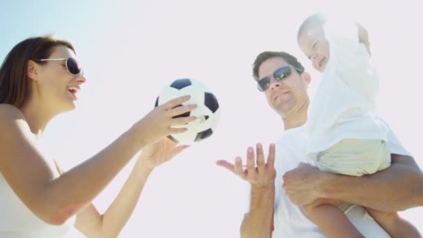 Родители с мальчиком играют в мяч на пляже — стоковое видео