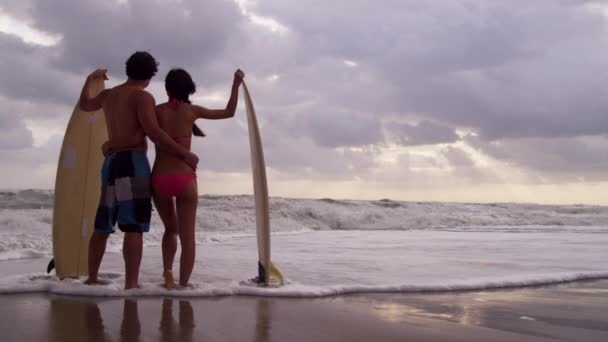 Pareja con tablas de surf en la playa — Vídeo de stock