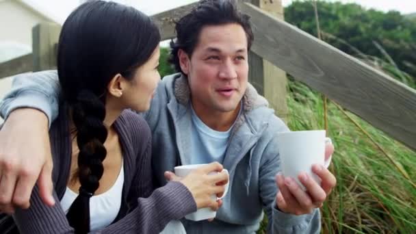 Couple on beach drinking coffee — Stock Video