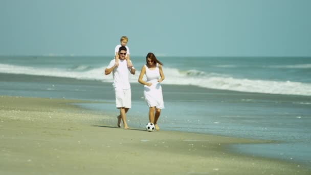 Rodzice z dzieckiem kopiąc piłkę na plaży — Wideo stockowe