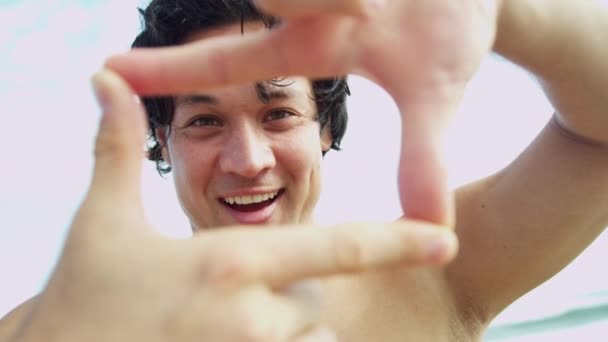 Чоловік на пляжі робить рамку для пальців — стокове відео