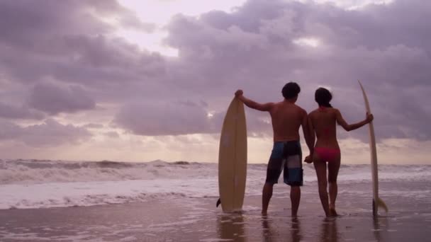 Pareja con tablas de surf en la playa — Vídeo de stock