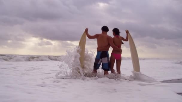 Pareja con tablas de surf en la playa — Vídeo de stock