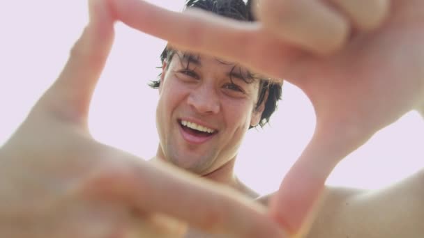 Uomo sulla spiaggia facendo cornice dito — Video Stock