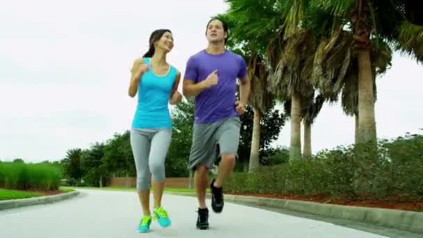 Pareja en ropa deportiva trotando en el parque — Vídeos de Stock