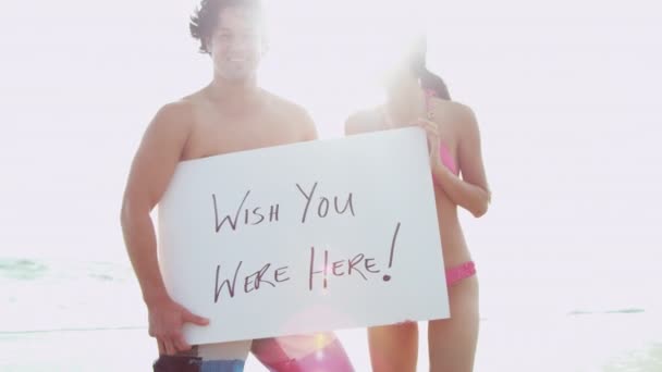 Casal na praia com placa branca — Vídeo de Stock