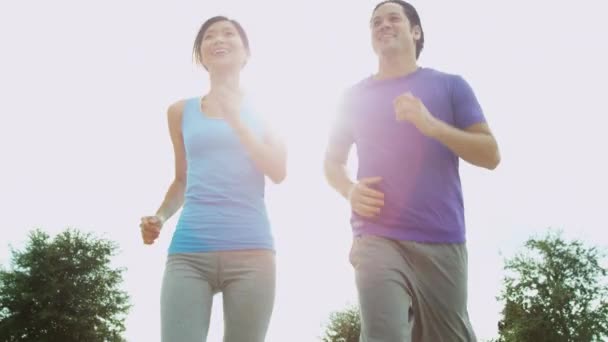 Pareja en ropa deportiva trotando en el parque — Vídeos de Stock