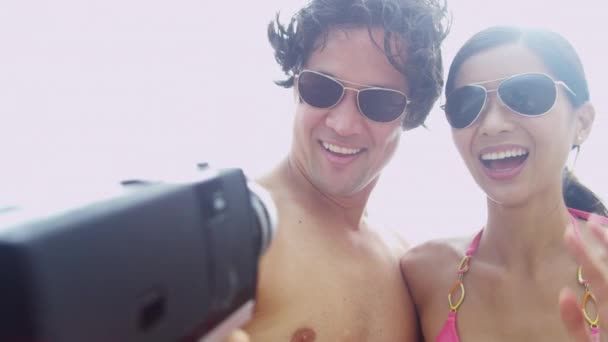 Pareja en la playa con cámara de vídeo — Vídeo de stock
