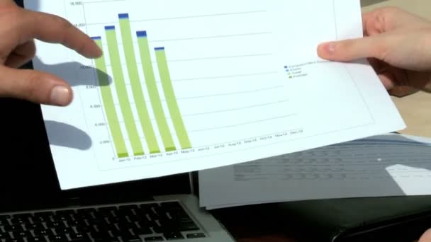 Zakenman en zakenvrouw kijken naar grafieken — Stockvideo