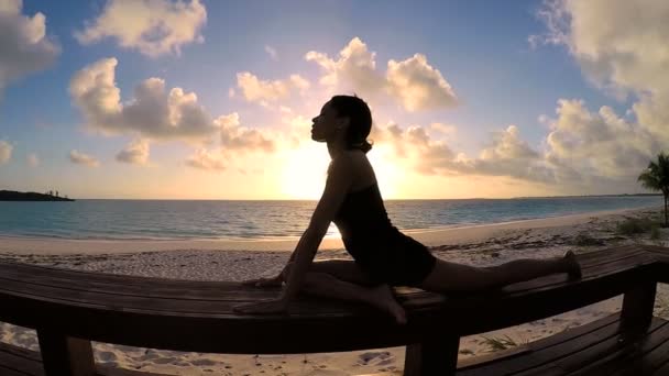 Jonge vrouw doet yoga op een strand — Stockvideo