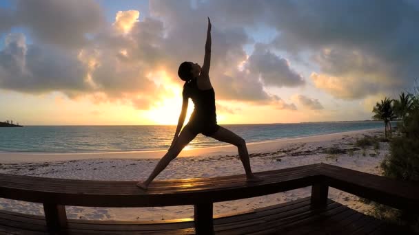 Молода жінка робить йогу на пляжі — стокове відео