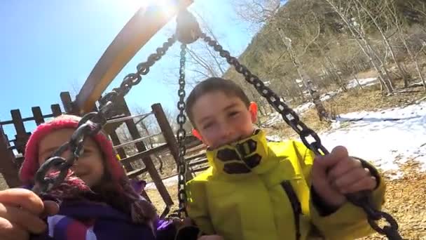 Crianças ao ar livre jogando no balanço no parque infantil — Vídeo de Stock