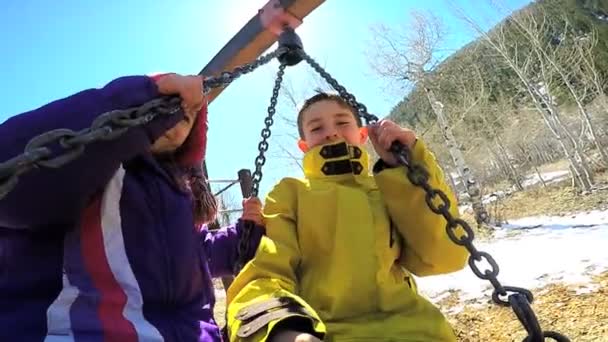 Kinderen buiten spelen op schommel in Speeltuin — Stockvideo