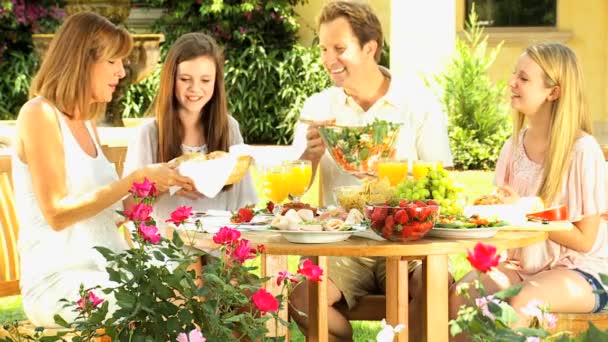 Eltern mit Töchtern beim Mittagessen im heimischen Garten — Stockvideo