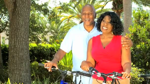 Etnische senior koppel houden passen op de fiets — Stockvideo