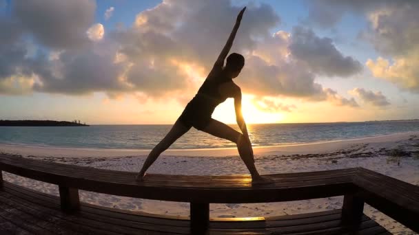 Young woman doing yoga on a beach — Stock Video