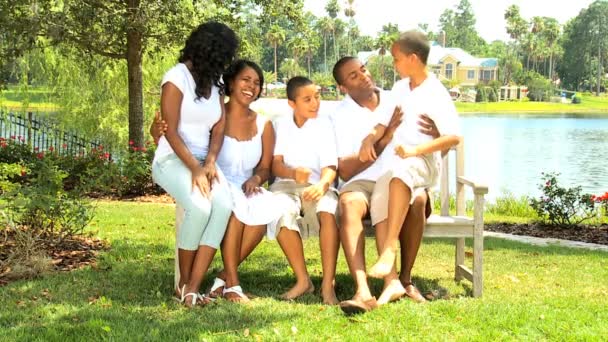 Афроамериканская семья на скамейке в саду — стоковое видео