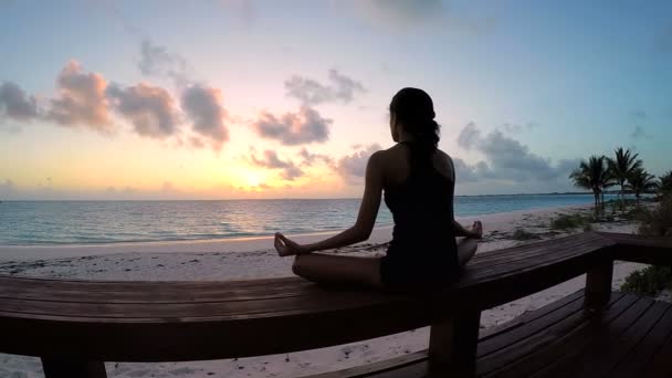 Jonge vrouw doet yoga op een strand — Stockvideo