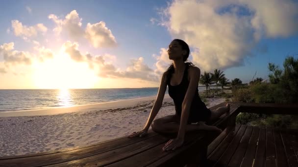 Ung kvinna gör yoga på en strand — Stockvideo