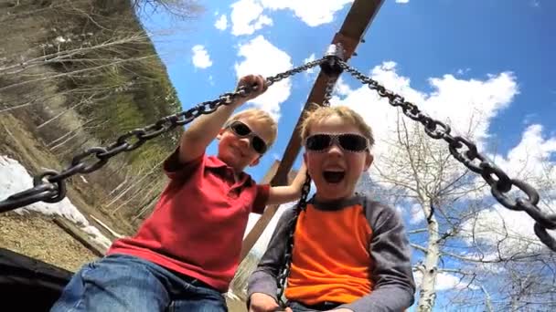 Young boys swinging on swing — Stockvideo