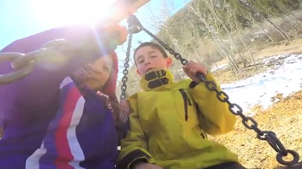 Niños al aire libre jugando en columpio en el patio de recreo — Vídeo de stock