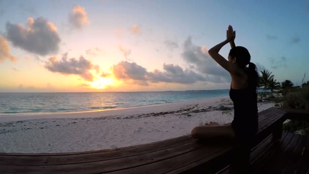 Mujer joven haciendo yoga en una playa — Vídeos de Stock
