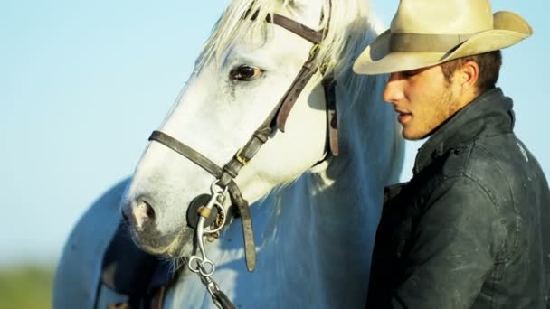 Чоловічий ковбой стоїть з білим конем — стокове відео