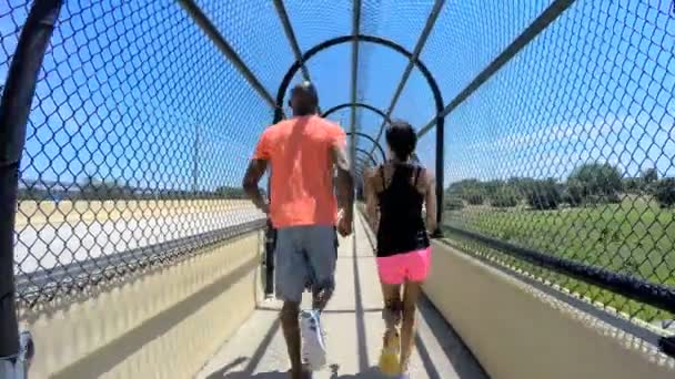 Pareja afroamericana trotando en pasarela vallada — Vídeos de Stock