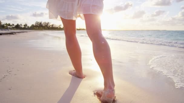 Жінка босоніж ходить на пляжі на заході сонця — стокове відео