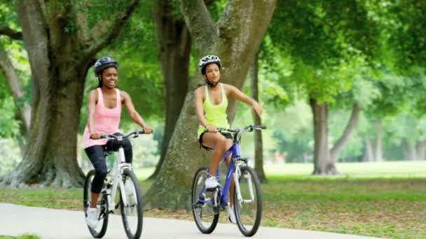 Multi ethnic women riding bicycles in park — Stock Video