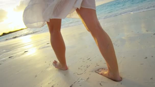 Vrouw blootsvoets lopen op het strand bij zonsondergang — Stockvideo