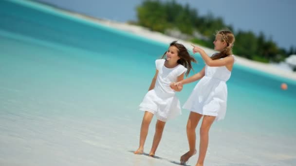 Meisjes in witte kleren wandelen op het strand — Stockvideo