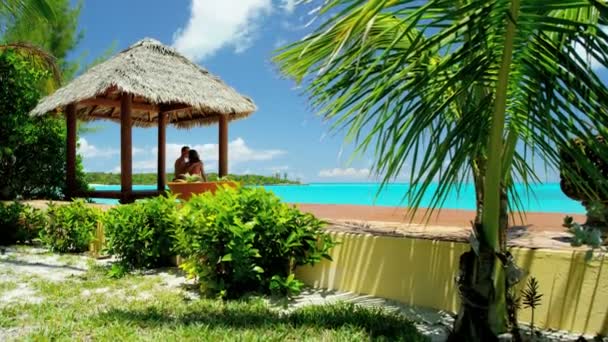 Pareja en thatched tiki cabaña en playa — Vídeo de stock