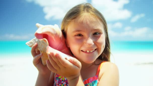 Meisje op een strand met een schelp — Stockvideo