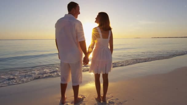 Καυκάσιος ζευγάρι σε τροπική παραλία στο ηλιοβασίλεμα — Αρχείο Βίντεο