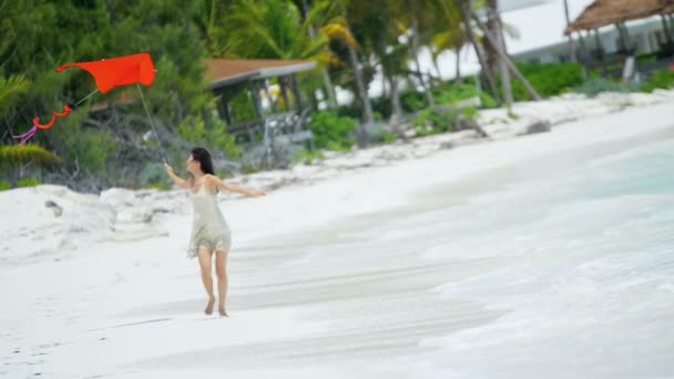 Азиатская девушка играет с красным змеем на пляже — стоковое видео