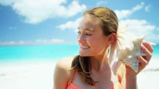 Tienermeisje op een strand met een schelp — Stockvideo