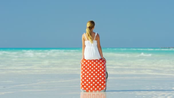 Młoda dziewczyna na plaży siedzi na walizkę — Wideo stockowe