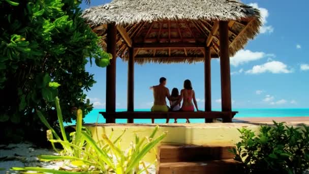 Familia en cabaña de paja tiki en la playa — Vídeo de stock