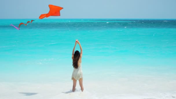 Asian girl playing with red kite on beach — Stock Video