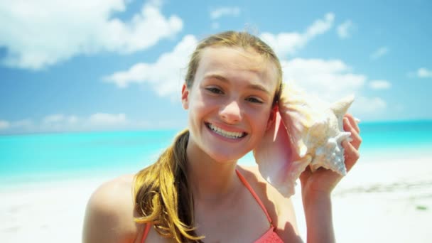 Adolescente em uma praia segurando uma concha — Vídeo de Stock