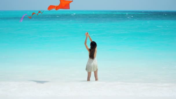 Asian girl playing with red kite on beach — Stock Video